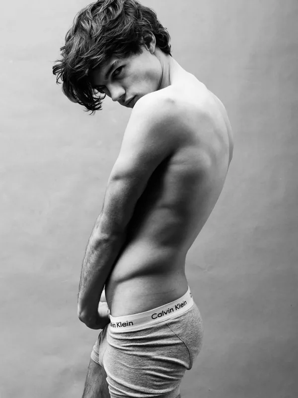 Jeune homme torse nu en sous-vêtements Calvin Klein, regardant l'objectif, photo en noir et blanc.
