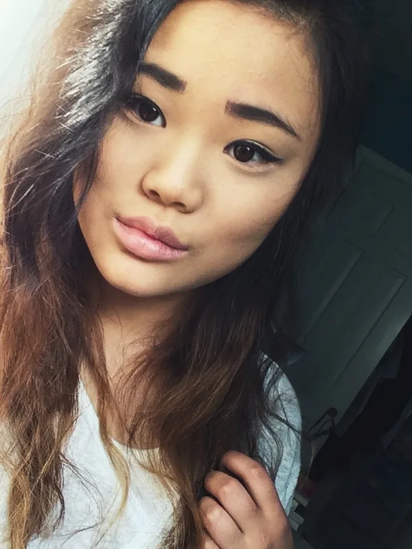 Jeune femme aux cheveux ombré regardant l'objectif dans une chambre éclairée par la lumière naturelle